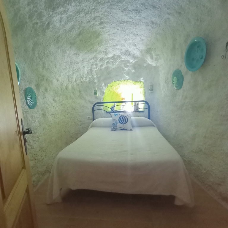 Unique cave house bedroom in Fontanar, Jaen with rustic stone walls and cozy decor.