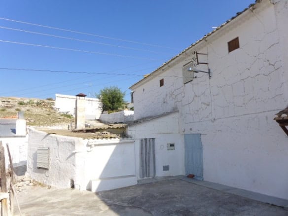 Cave house in La Alqueria, Granada with whitewashed walls and traditional architecture.