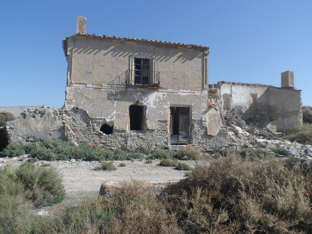 Abandoned stone house with weathered walls and rustic charm in Venta del Peral, Granada.