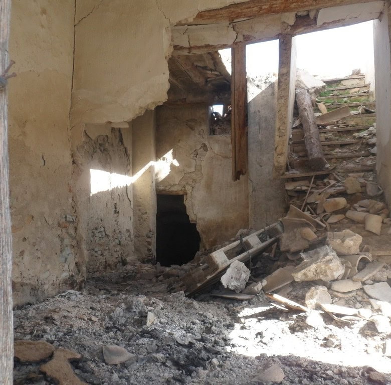 Old stone house ruins in Venta del Peral, Granada, with damaged walls and debris.