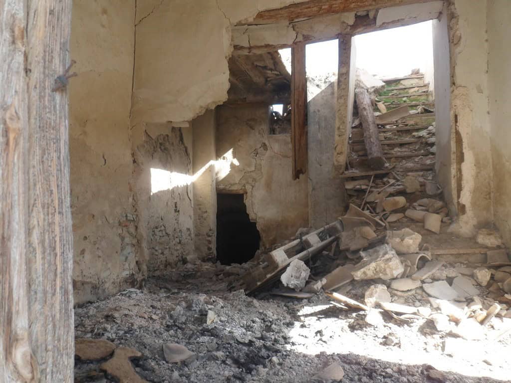 Old stone house ruins in Venta del Peral, Granada, with damaged walls and debris.