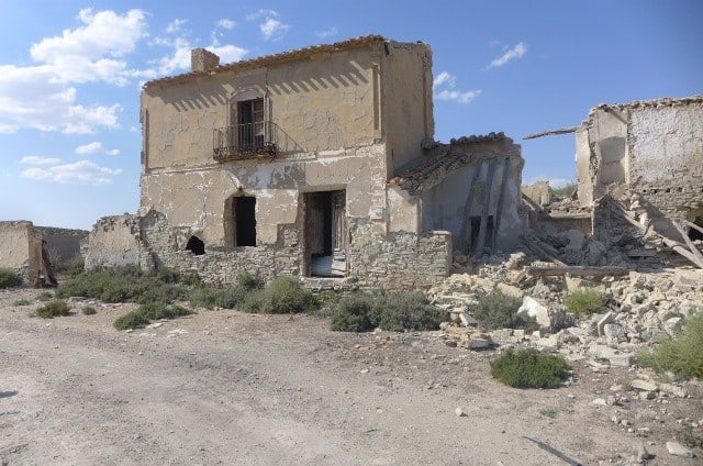 Abandoned rural house in Venta del Peral, Granada, with damaged walls and surrounding ruins. Ideal f.