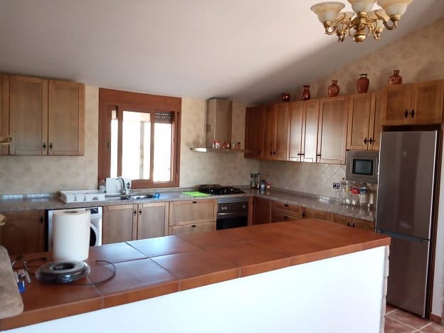Country estate kitchen with wooden cabinets and modern appliances in Fontanar, Jaen.