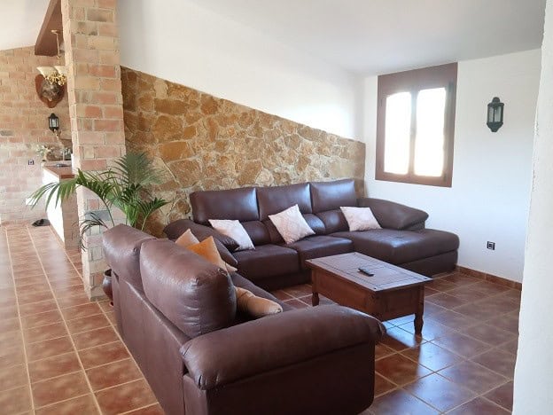 Elegant country estate living room with leather sofas and rustic stone wall.