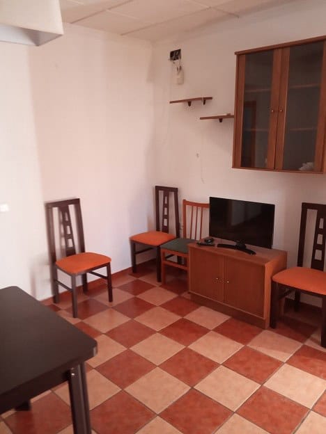 Comfortable living space with wooden chairs, TV, and shelves in Gor, Granada.