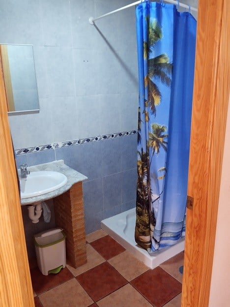 Compact bathroom with shower and tropical-themed curtain in Gor, Granada.