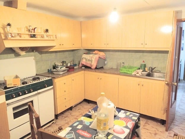 Kitchen in Hinojares village with wooden cabinets and basic appliances.