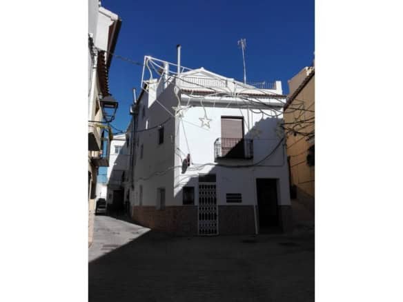 White house in Seron, Almeria with holiday decorations and narrow alleyway.