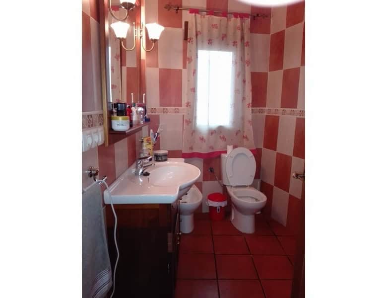 Bathroom with pink checkered tiles, sink, toilet, and window in Seron, Almeria.