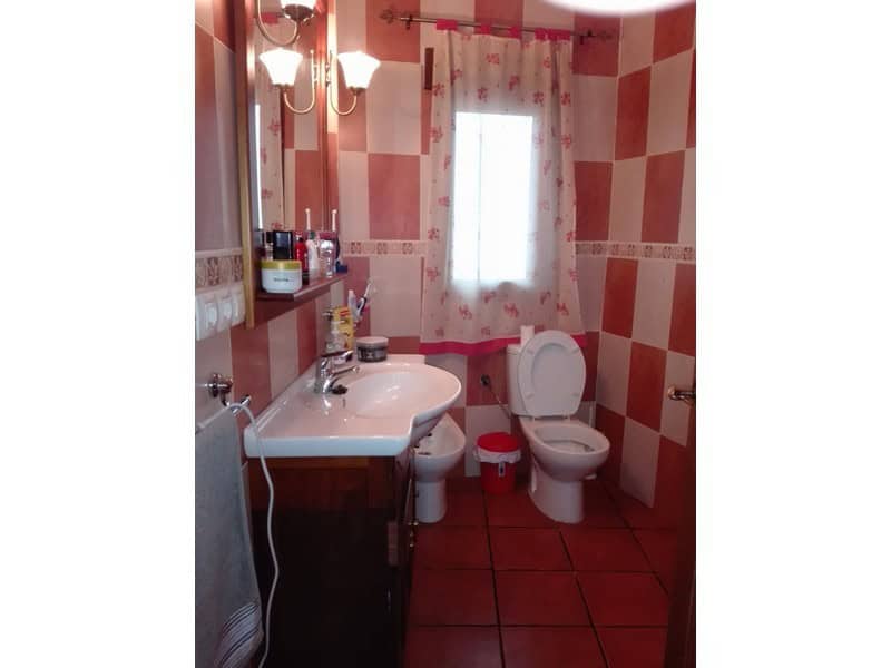 Bathroom with pink checkered tiles, sink, toilet, and window in Seron, Almeria.