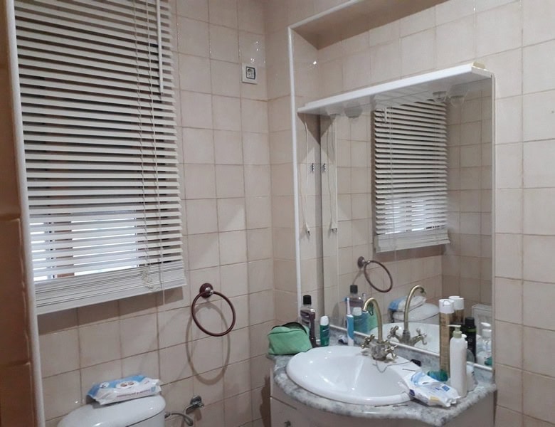 Almeria town house bathroom with sink, mirror, and window with blinds.