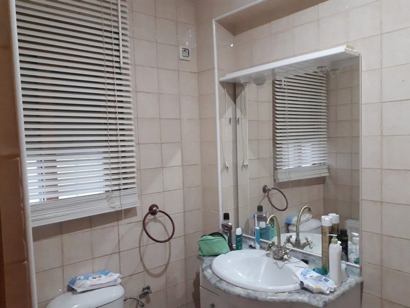 Almeria town house bathroom with sink, mirror, and window with blinds.