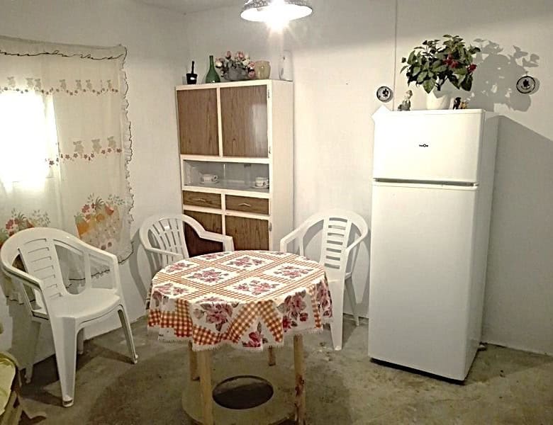Cozy kitchen with white furniture, a round table with a floral tablecloth, and plastic chairs in a r.