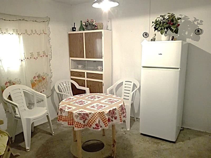 Cozy kitchen with white furniture, a round table with a floral tablecloth, and plastic chairs in a r.