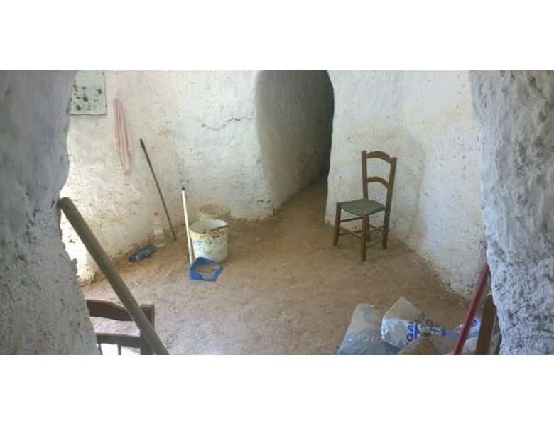 Traditional cave house interior with rustic walls and simple furnishings in Baza, Granada.