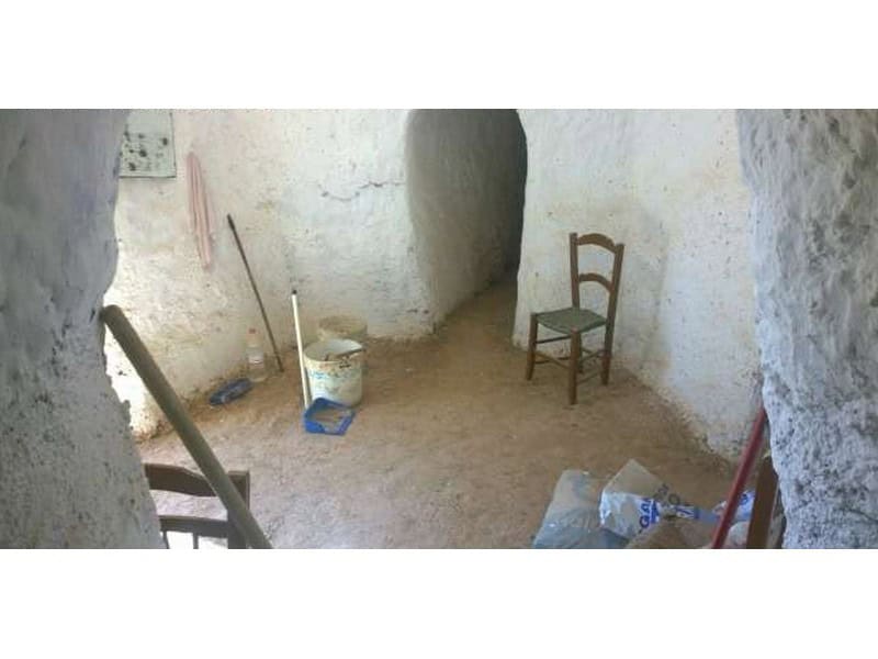 Traditional cave house interior with rustic walls and simple furnishings in Baza, Granada.