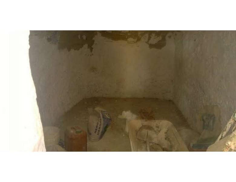 Cave house interior in Baza, Granada, showing unfinished stone walls and construction materials.