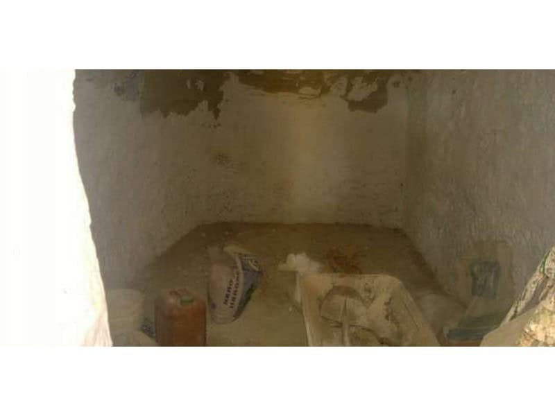 Cave house interior in Baza, Granada, showing unfinished stone walls and construction materials.
