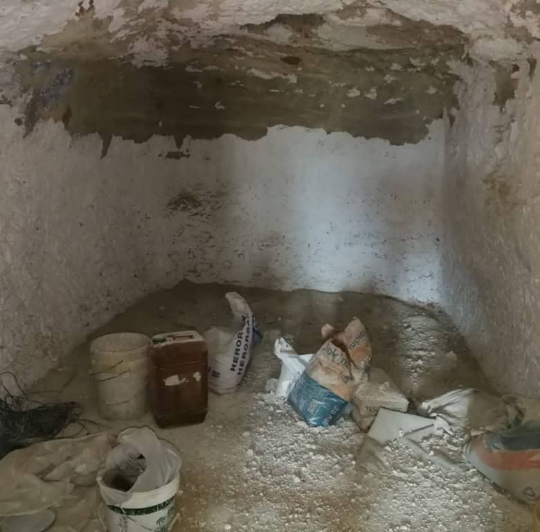 Interior view of a cave house in Baza, Granada, showing rough stone walls and construction materials.