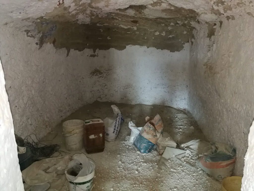 Interior view of a cave house in Baza, Granada, showing rough stone walls and construction materials.