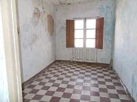 Old room with worn walls and checkered floor tiles in a village property in Seron, Almeria.