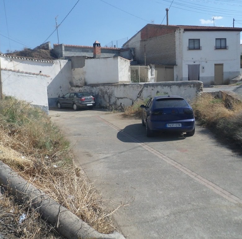 Cave house in Guadix, Granada, with parking area and traditional white buildings.