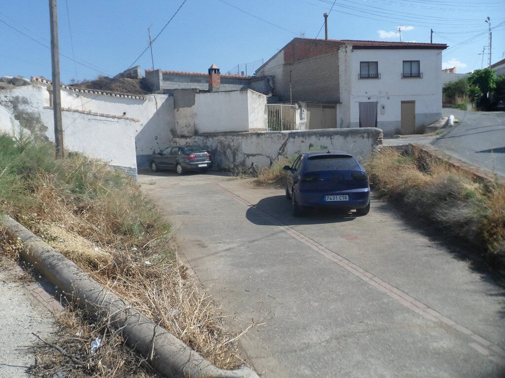Cave house in Guadix, Granada, with parking area and traditional white buildings.