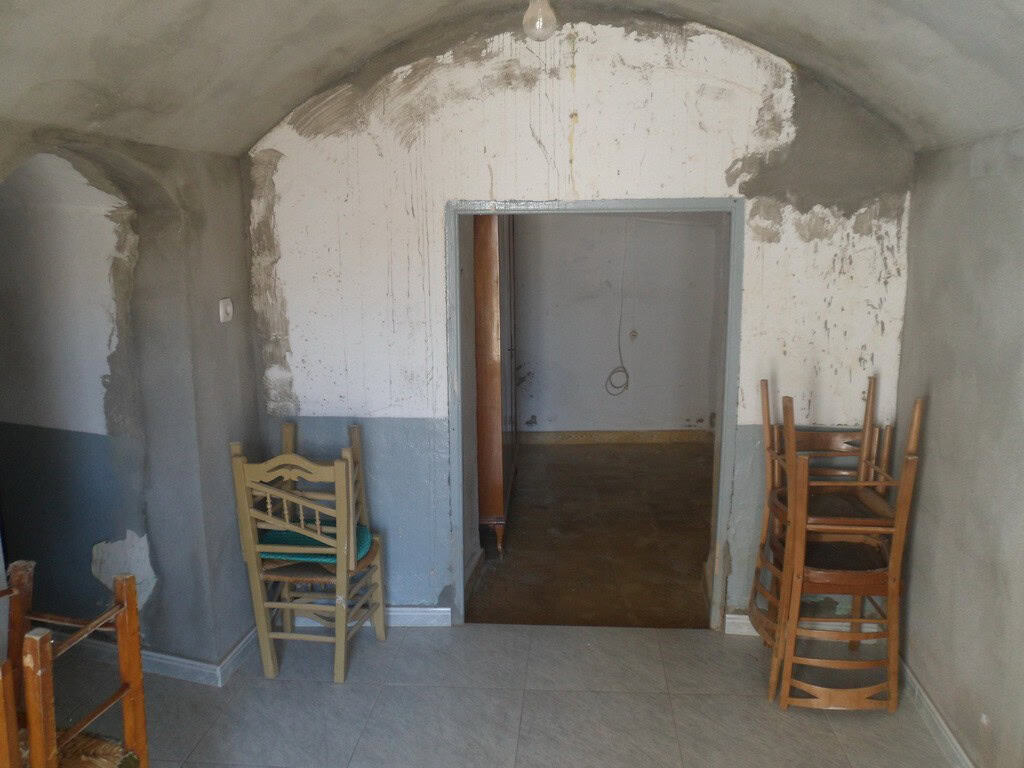 Cave house interior in Guadix, Granada, showcasing rustic stone walls and wooden chairs.