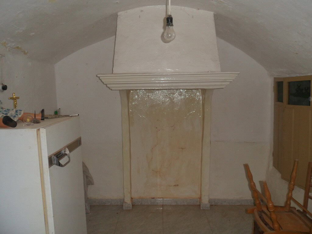 Charming cave house interior in Guadix, Granada, featuring a rustic fireplace and cozy living space.