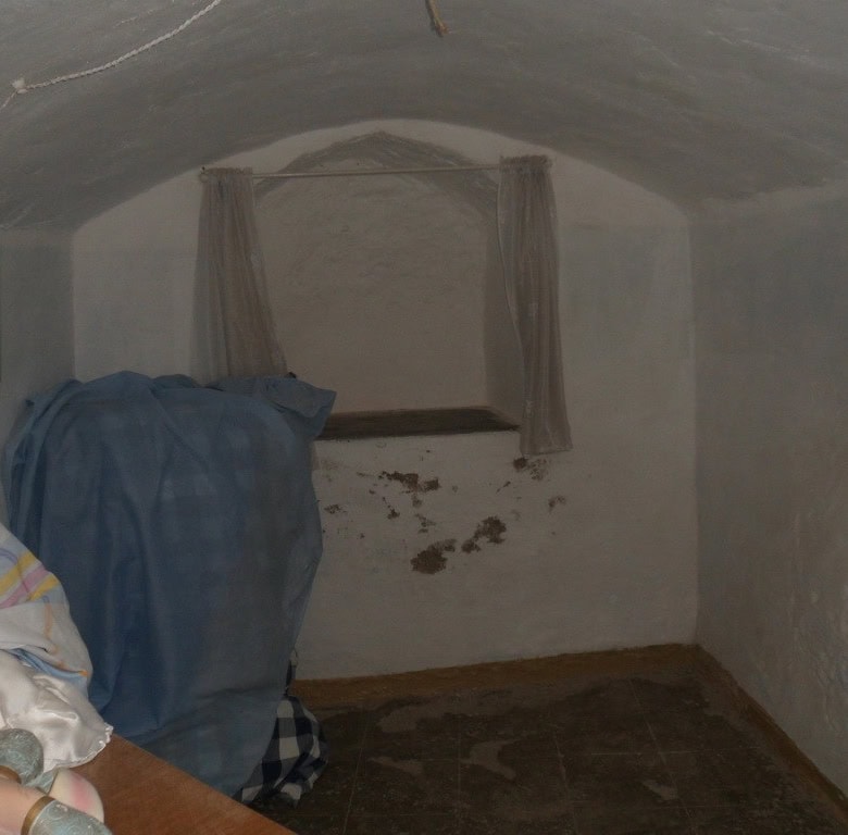 Unique cave house interior in Guadix, Granada, with whitewashed walls and small window.