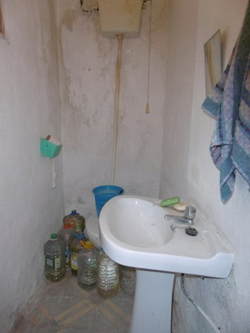 Old bathroom with sink and water bottles in Tijola, Almeria.