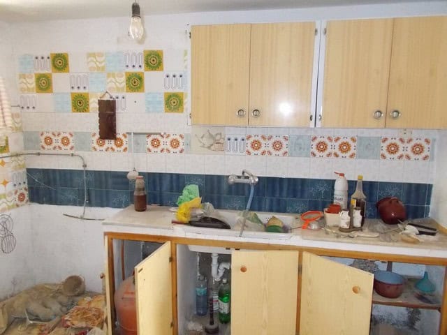 Charming rural property kitchen in Seron, Almeria with rustic cabinets and colorful tiled backsplash.