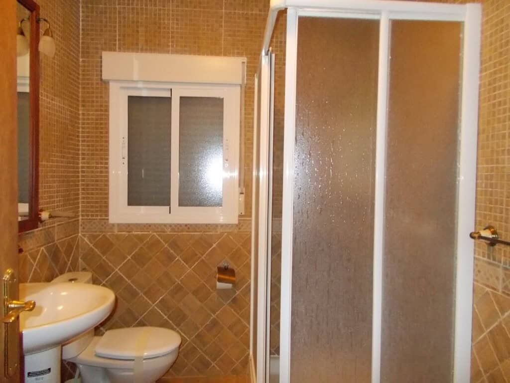 Cozy bathroom in a village property in Seron, Almeria, featuring a shower, toilet, and sink with til.