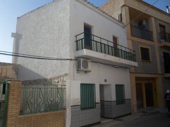 Town house with balcony in Freila, Granada, Spain, featuring white exterior walls and green accents.