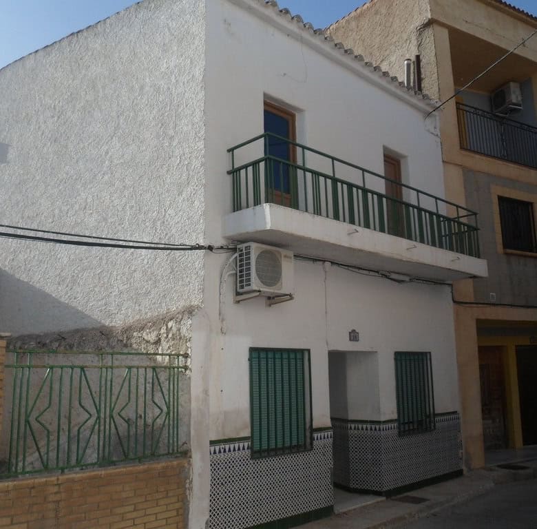 Town house with balcony in Freila, Granada, Spain, featuring white exterior walls and green accents.