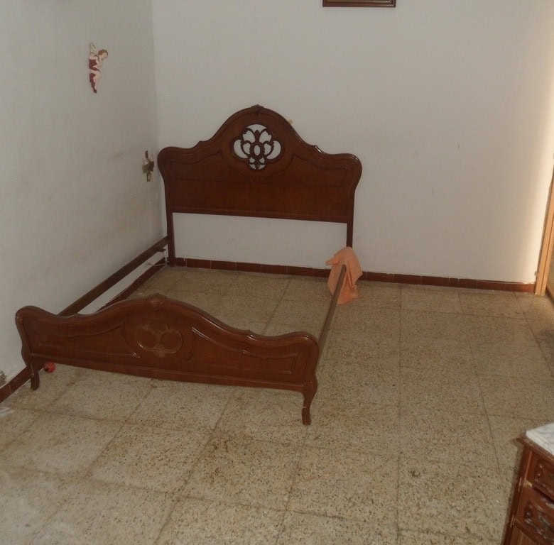Bedroom with wooden bed frame in a town house in Freila, Granada.