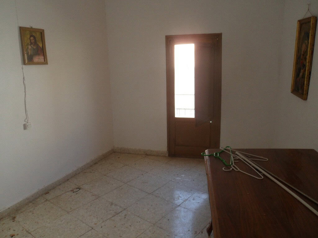Charming interior of a town house in Freila, Granada, featuring a simple room with religious artwork.