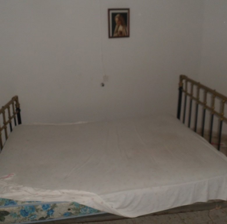 Charming town house in Freila, Granada, featuring a simple bedroom with a metal bed frame and a reli.