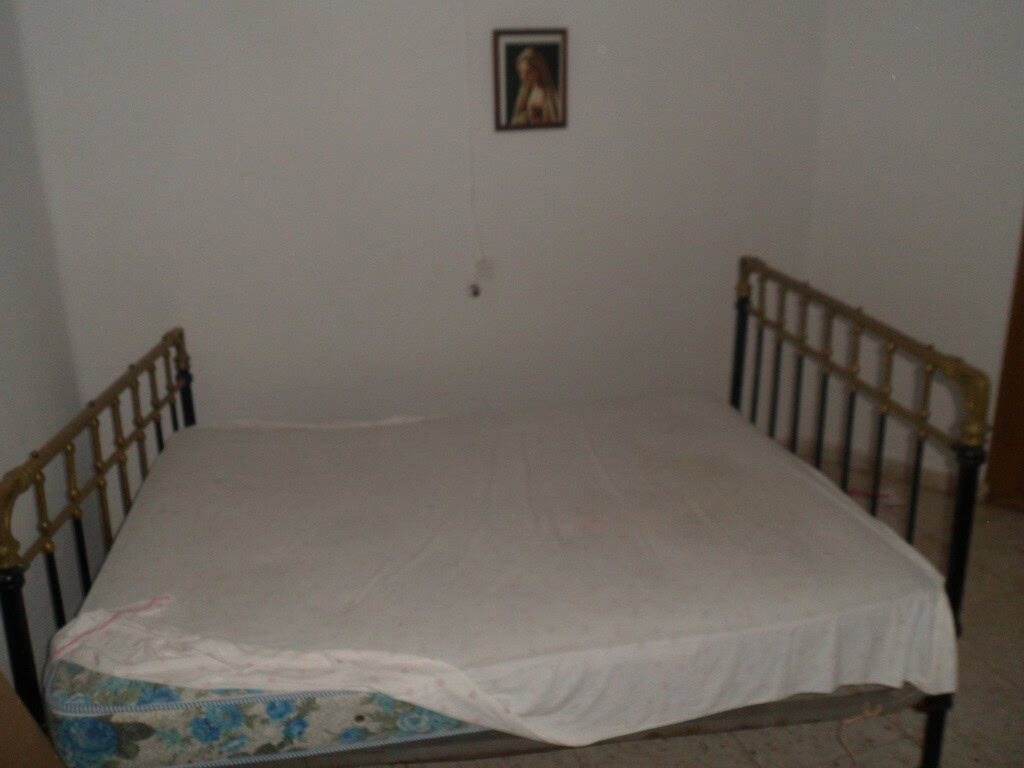 Charming town house in Freila, Granada, featuring a simple bedroom with a metal bed frame and a reli.