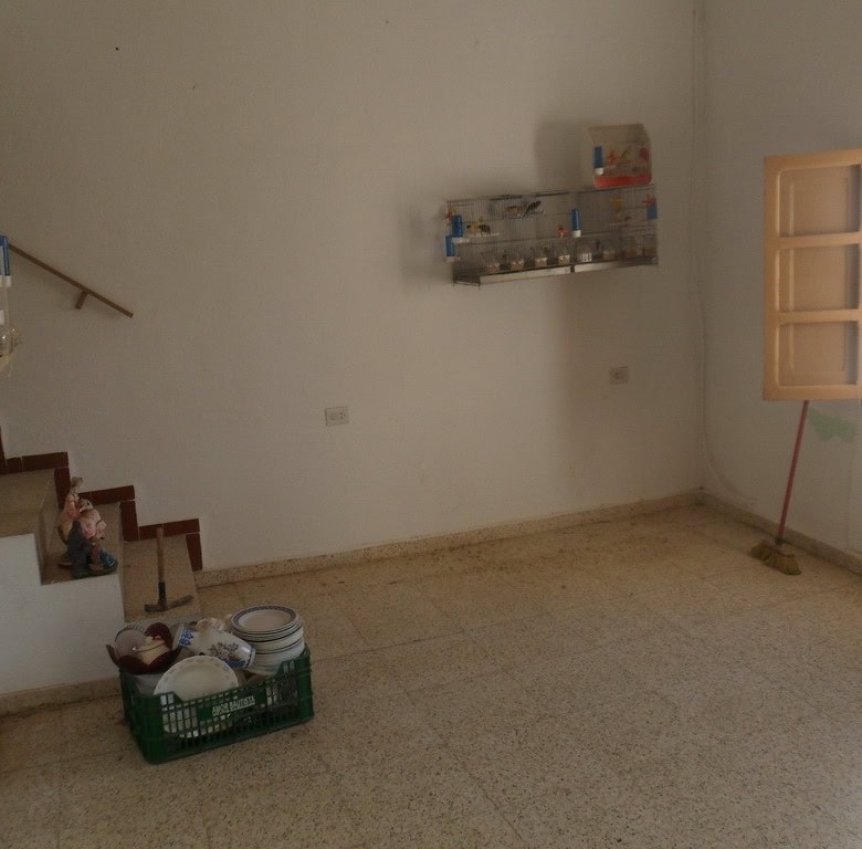 Interior view of a town house in Freila, Granada, showing a simple, unfurnished room with a window a.