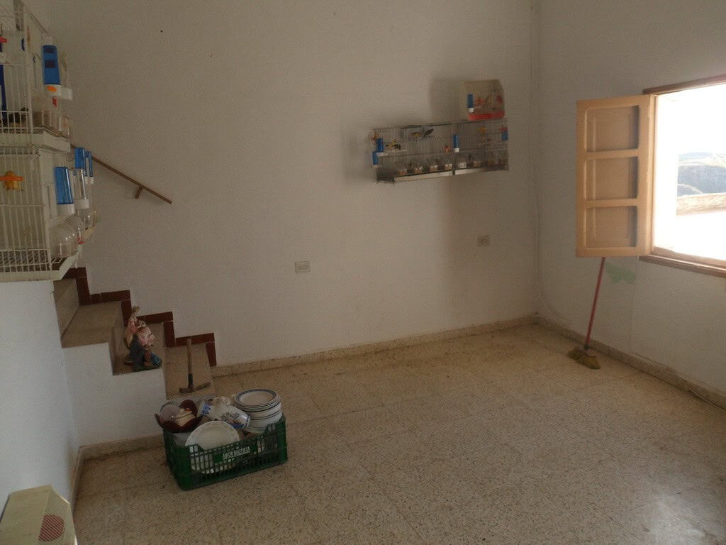 Interior view of a town house in Freila, Granada, showing a simple, unfurnished room with a window a.