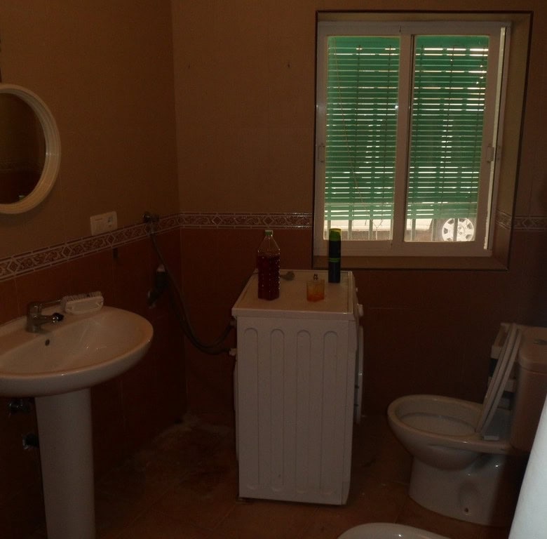 Bathroom with sink, toilet, and window in Freila town house.