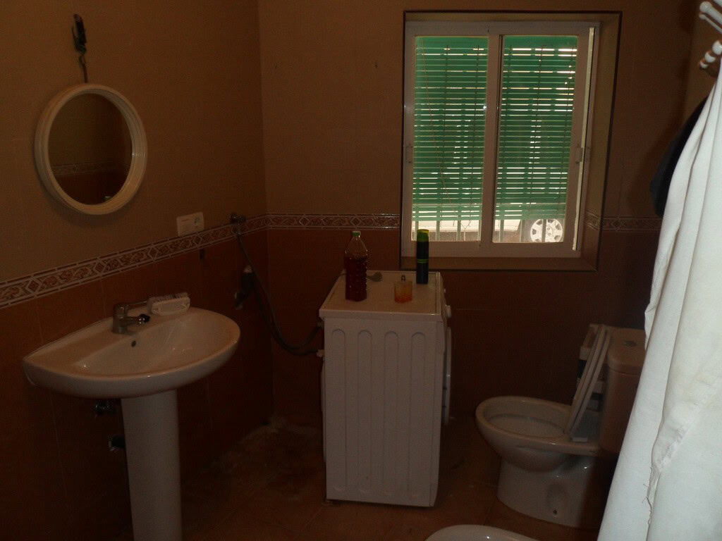 Bathroom with sink, toilet, and window in Freila town house.