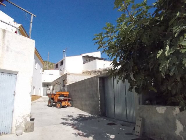 Village property in Lucar, Almeria with white buildings and a tractor on a sunny day.
