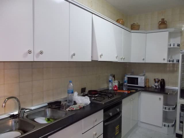 Village kitchen with white cabinets and modern appliances in Cela, Almeria.