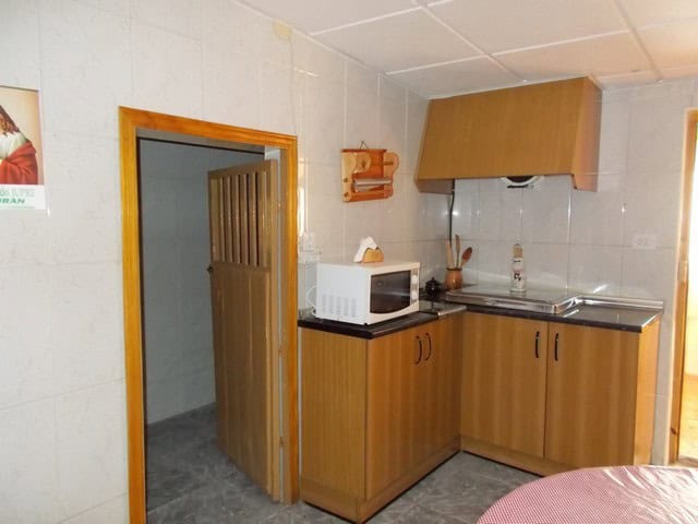 Village Property Kitchen in Zujar, Granada with compact appliances and wooden cabinets.