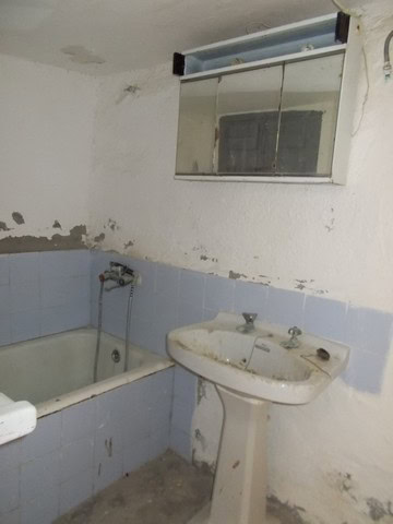 Interior of a rustic bathroom in Tijola, Almeria, with an old bathtub and sink.