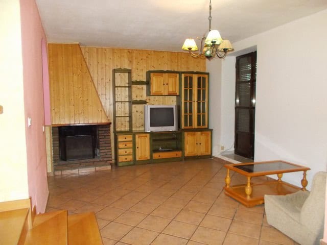 Spacious living room with fireplace, wooden cabinets, and comfortable seating in Tijola, Almeria.