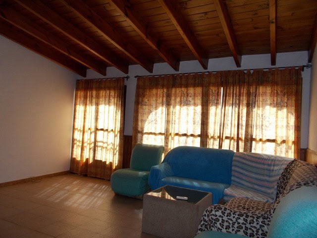 Interior view of a cozy town house living room in Tijola, Almeria, featuring wooden ceiling, colorfu.
