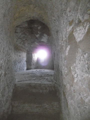 Cave house interior with natural stone walls and a light at the tunnel's end in Benamaurel, Granada.